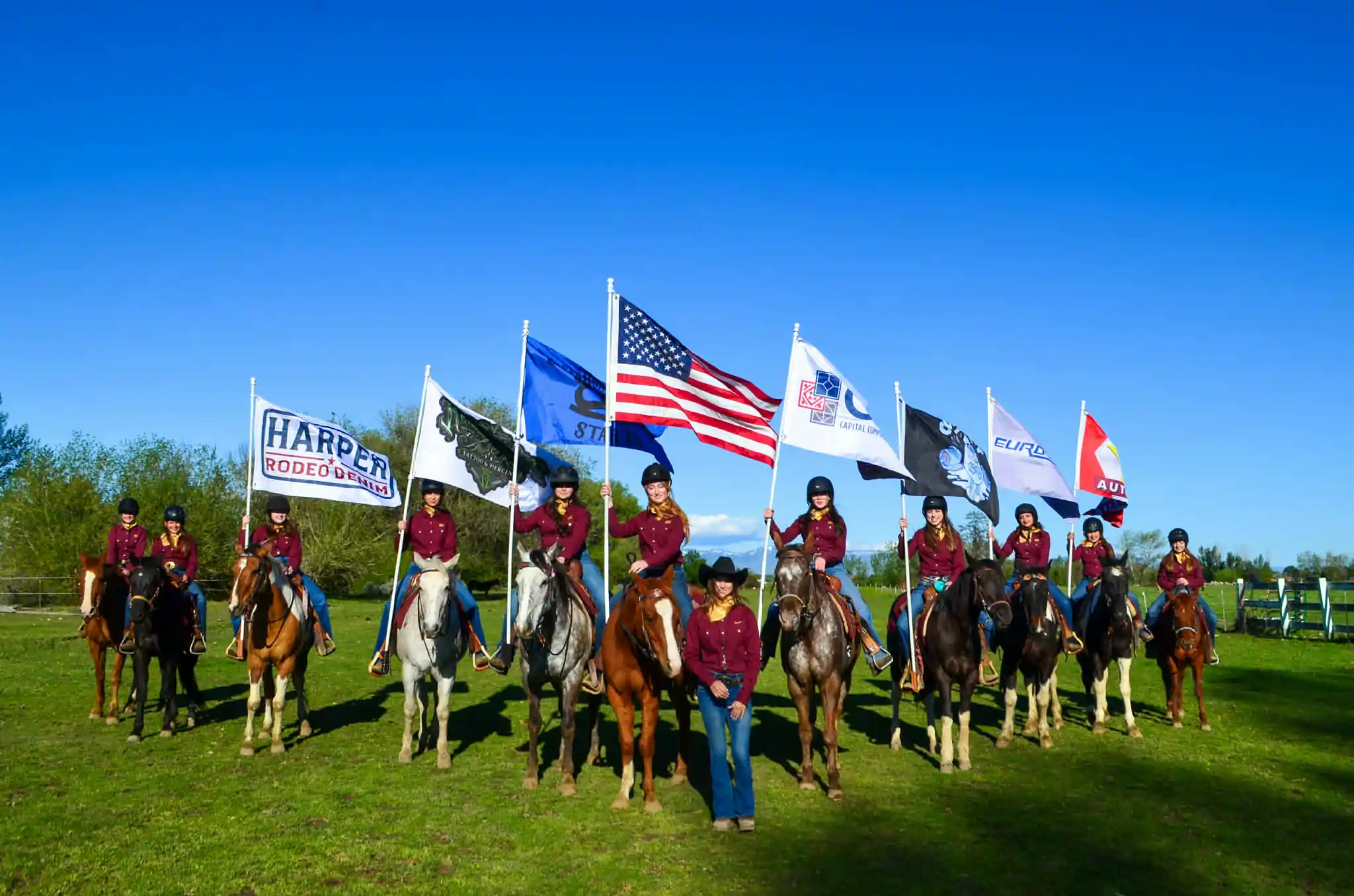 The Broken Road Ranch barrel racing team carrying the American flag and Harper Rodeo Denim flag